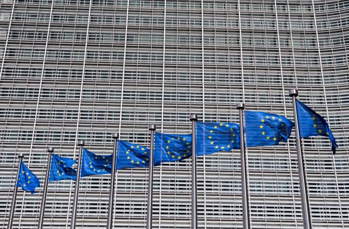 banderas europeas con edificio de la comisión europea al fondo